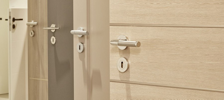 Mehrere nebeneinander angeordnete Türblätter in unterschiedlichen Farbtönen (weiß, holzähnlich, grau) mit integrierten Türgriffen.