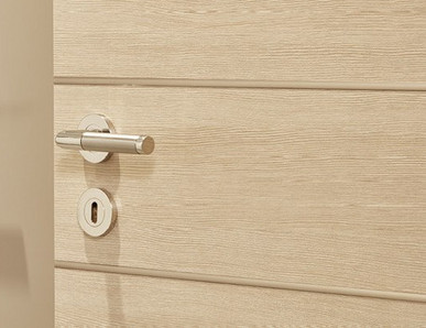 Mehrere nebeneinander angeordnete Türblätter in unterschiedlichen Farbtönen (weiß, holzähnlich, grau) mit integrierten Türgriffen.