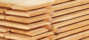 Gestapelte Schalbretter aus Holz mit sägerauer Oberfläche, ideal für den Bau- und Konstruktionsbereich.