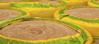 Gerollte Dämmwolle in gelb-grüner Verpackung, bereit für den Einsatz in Wärmedämmung und Schallschutz.