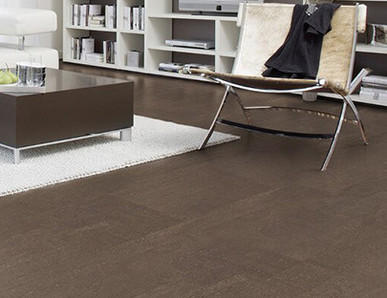 Der Boden im Wohnzimmer ist mit schokoladenfarbenem Kork ausgelegt. Weiter hinten stehen ein Sofa, ein Couchtisch und ein Sessel.