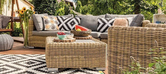 Gemütliche Gartenmöbel mit bunten Kissen auf einer Terrasse