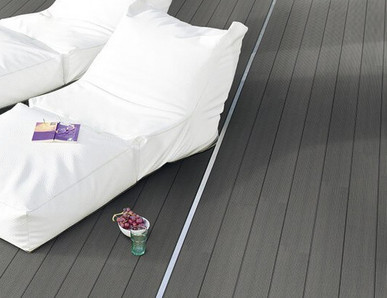 Graue WPC-Terrasse neben einem Pool mit zwei weißen Sonnenliegen.