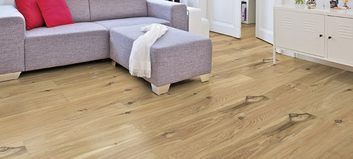 Im Wohnzimmer ist Parkett in Langdielen-Optik verlegt. Dazu passt ein Ecksofa mit bunten Kissen.