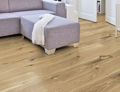 Im Wohnzimmer ist Parkett in Langdielen-Optik verlegt. Dazu passt ein Ecksofa mit bunten Kissen.