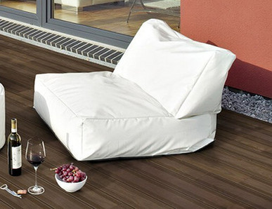 Dunkle Holzterrasse neben einem Gebäude mit zwei Sitzkissen und dekorativen Elementen.