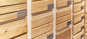 Ausstellung von verschiedenen gehobelten Holzprofilen mit Beschriftung, geeignet für Fassaden- und Innenverkleidung.