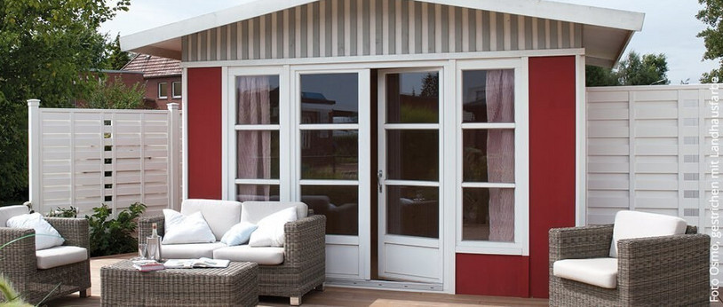 Gartenhaus mit angrenzender Terrasse, ausgestattet mit Gartenmöbeln, umgeben von einem grünen Garten.