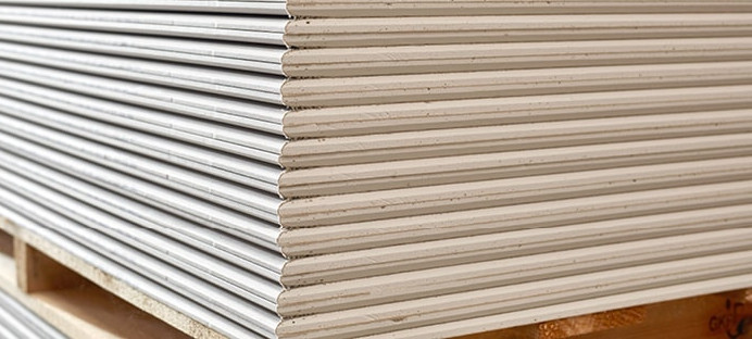 Gestapelte Gipsfaserplatten auf einer Holzpalette, bereit für den Einsatz im Trockenbau.