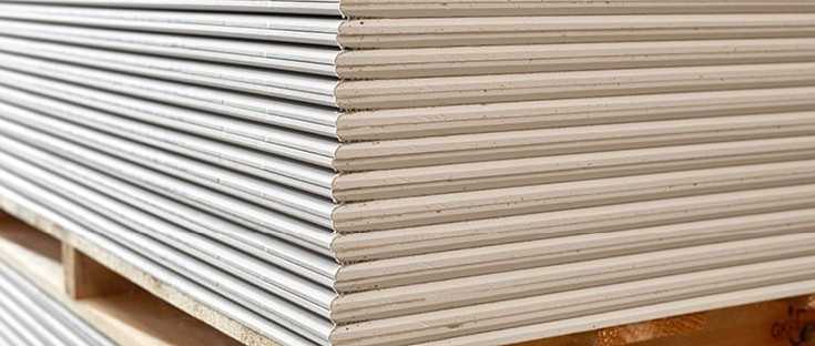 Gestapelte Gipsfaserplatten auf einer Holzpalette, bereit für den Einsatz im Trockenbau.