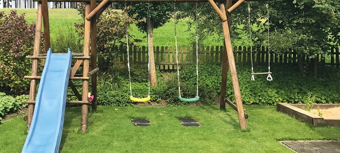 Spielgeräte: Schaukel und Rutsche für Kinder im Garten.