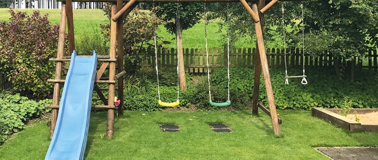 Spielgeräte: Schaukel und Rutsche für Kinder im Garten.