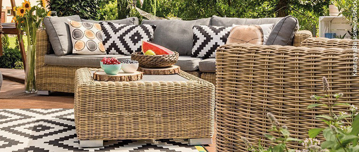 Gemütliche Gartenmöbel mit bunten Kissen auf einer Terrasse