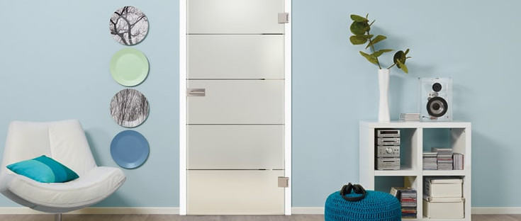 Glastür aus satiniertem Glas mit vier quer verlaufenden Streifen. Die Tür steht vor einer blauen Wand. Links und rechts sind dekorative Elemente sichtbar.