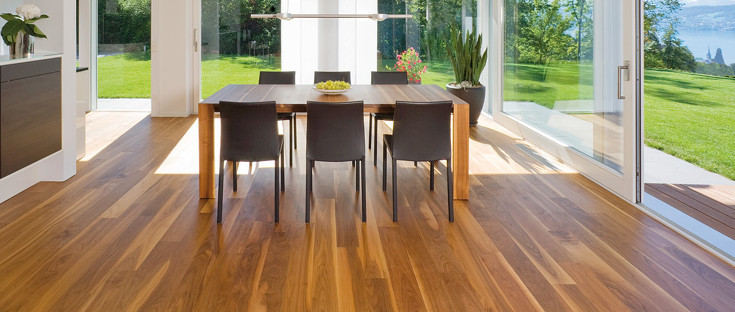 Die Küche ist mit massivem Boden ausgelegt. In der Mitte steht ein massiver Tisch mit Stühlen, und durch die Glasfenster sieht man den Ausgang zur Terrasse und zum Garten.