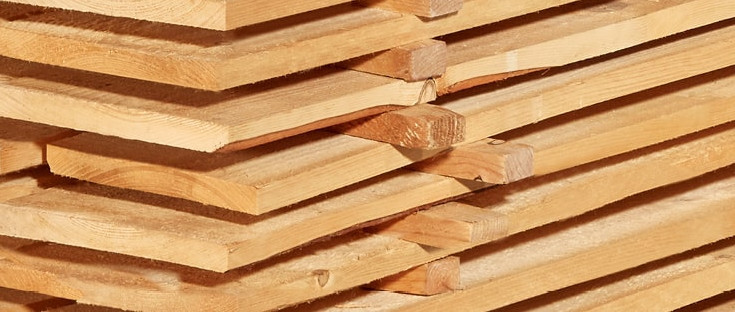 Gestapelte Schalbretter aus Holz mit sägerauer Oberfläche, ideal für den Bau- und Konstruktionsbereich.